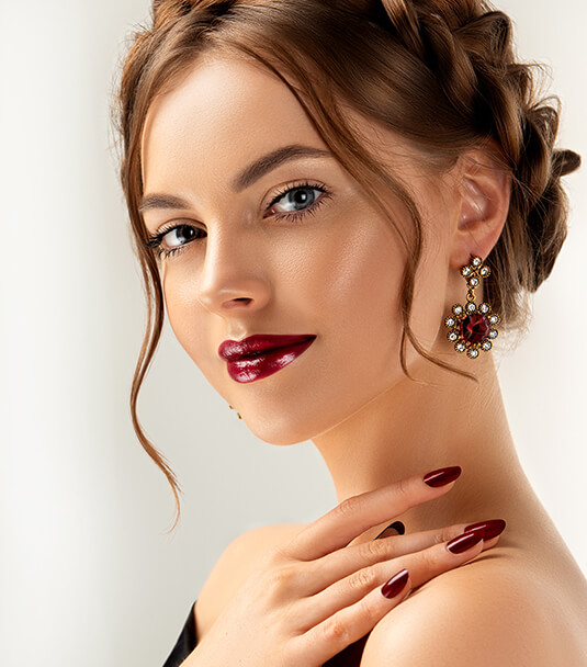 imagem de modelo feminina em perfil, com um brinco comprido de pedras vermelhas e brancas.